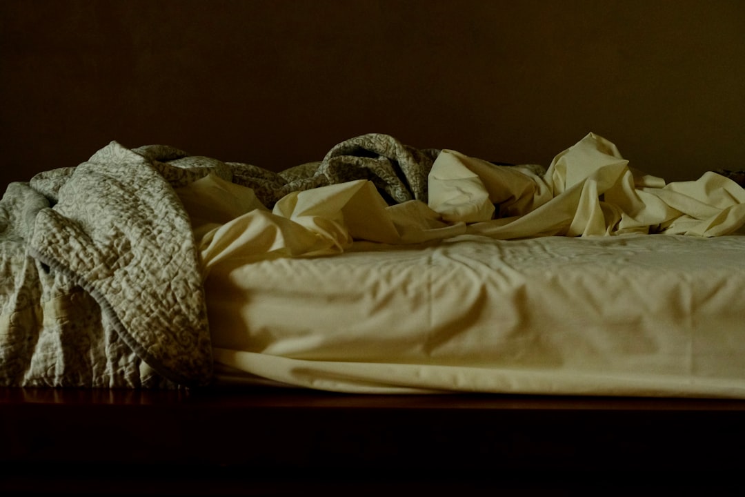 a cluttered bedroom floor in a NYC apartment with clothes, bags, and miscellaneous items before a clean-out, natural daylight from a window