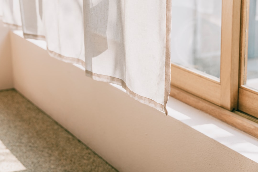 Open window in a prewar NYC apartment with sheer curtain and late-afternoon sunlight on the sill