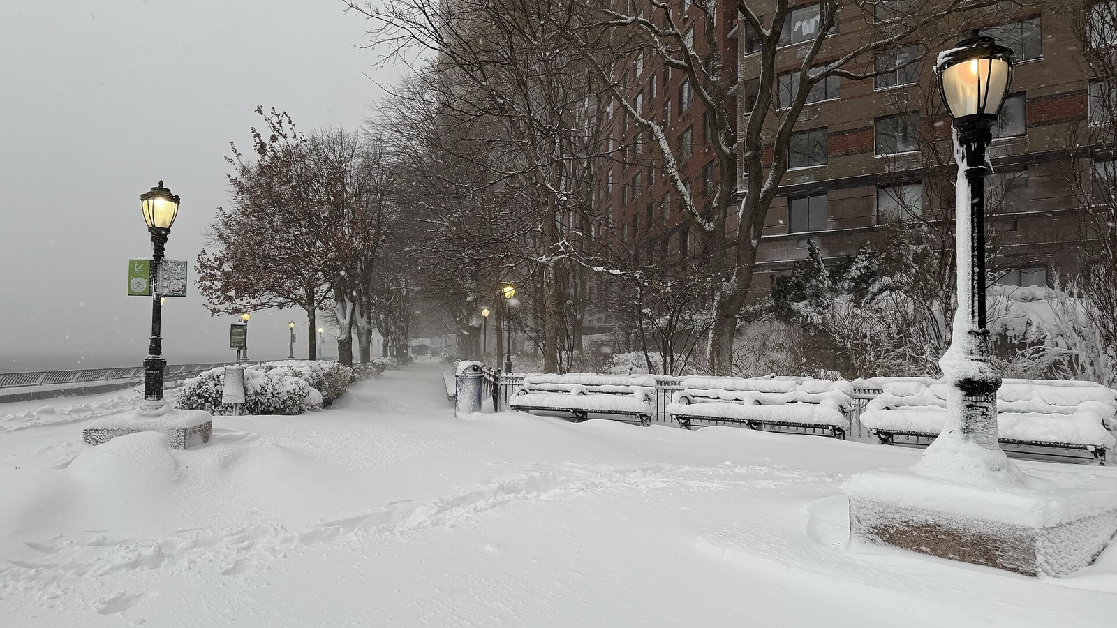 The Hudson River Esplanade at Battery Park City during winter, looking south along the waterfront promenade with views toward the Statue of Liberty