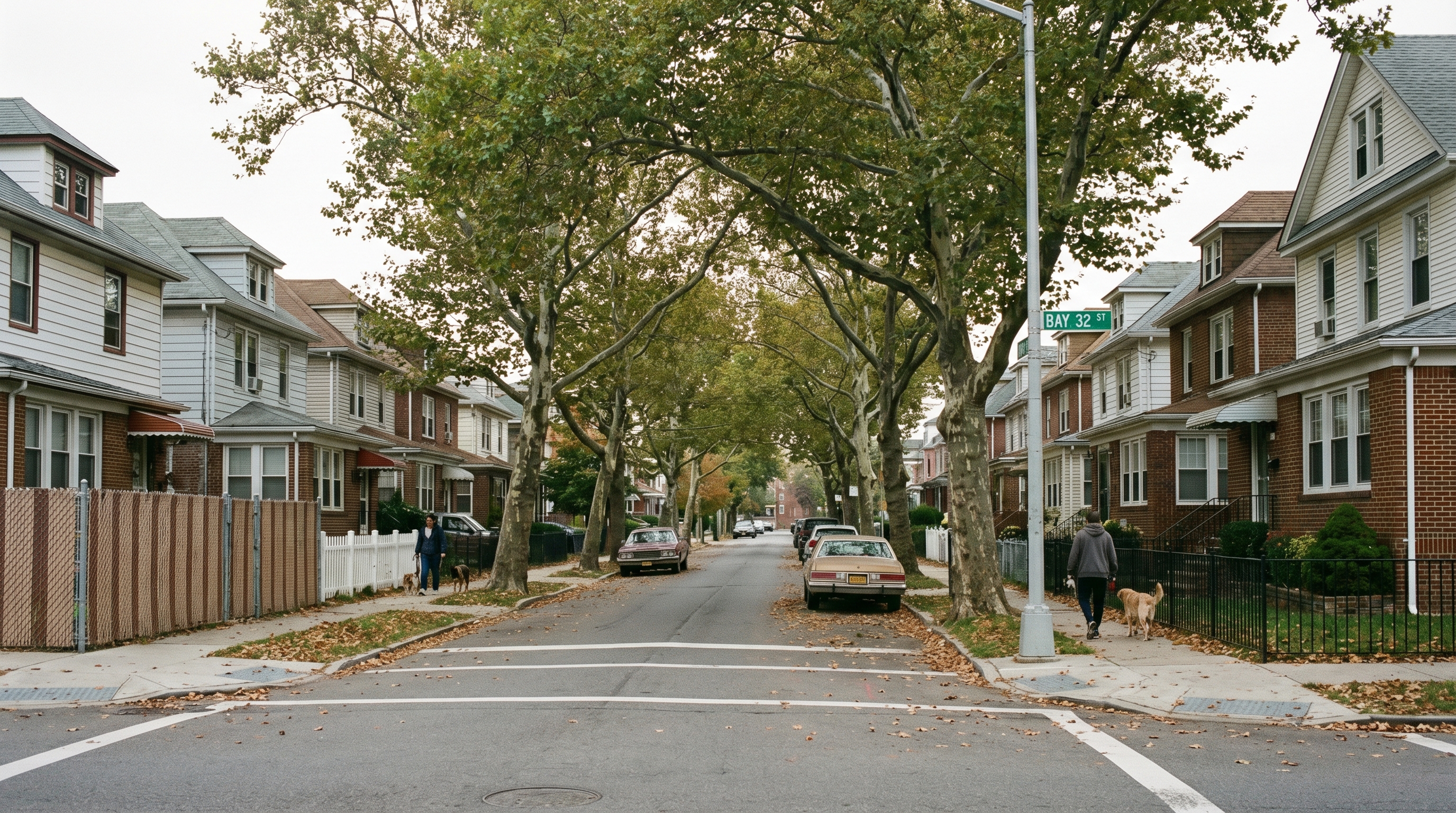 Quiet residential street in Bayswater Queens with single-family and two-family homes, mature trees, and Bay 32nd Street sign