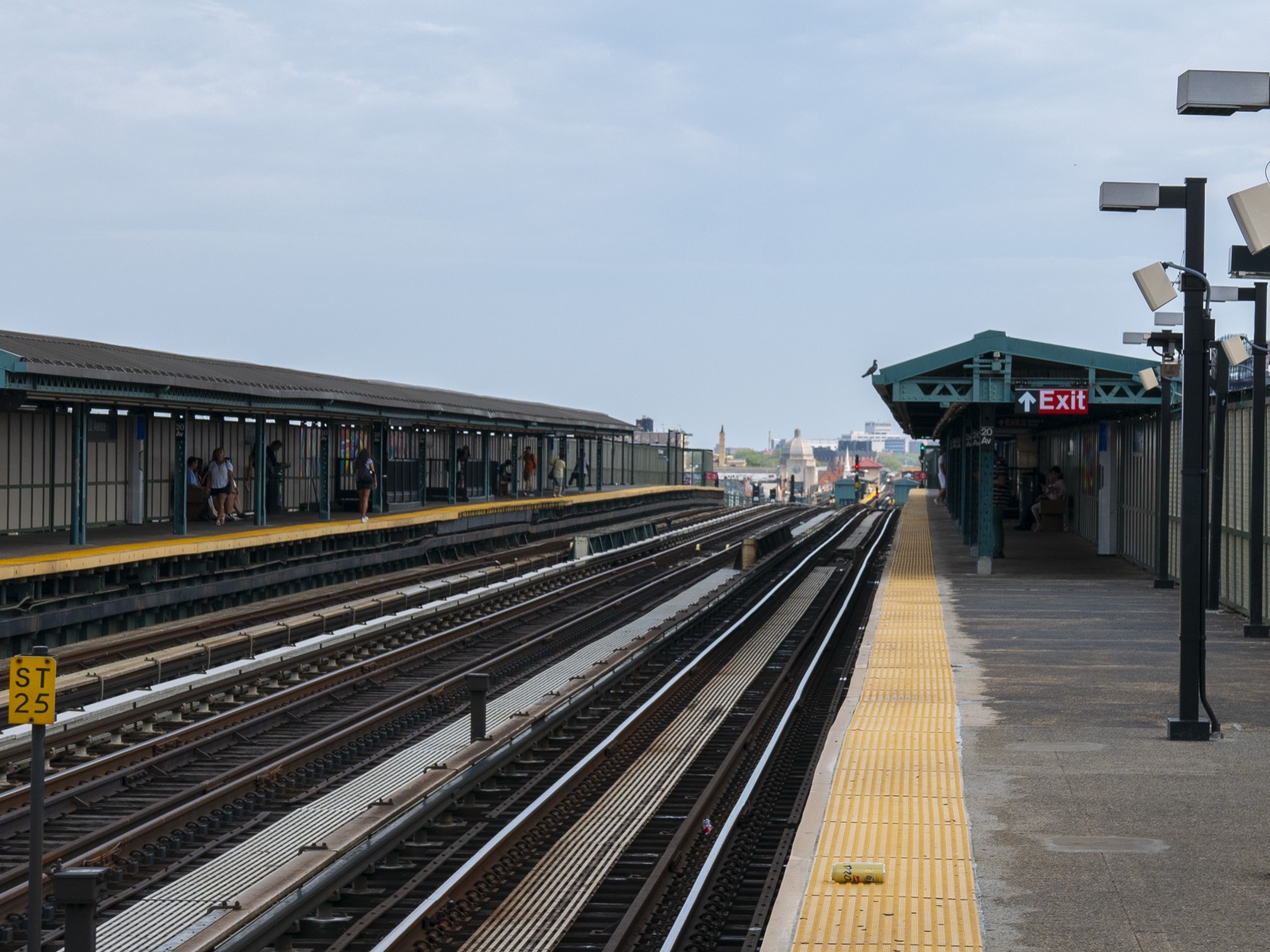 The elevated BMT West End Line running above 86th Street near 20th Avenue in Bensonhurst, the steel structure that defines the commercial corridor below and has shaped the streetscape since 1916