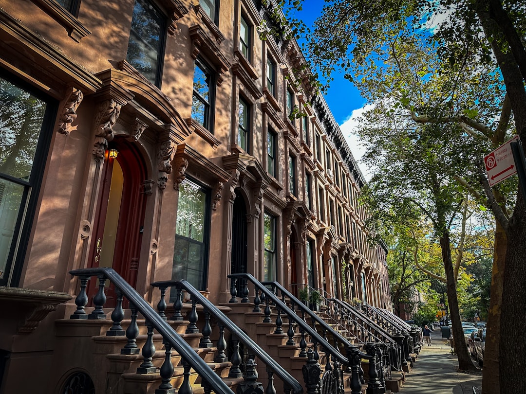 Attached brick row houses on a Brooklyn residential block, characteristic two-family interwar construction with stoops and iron railings