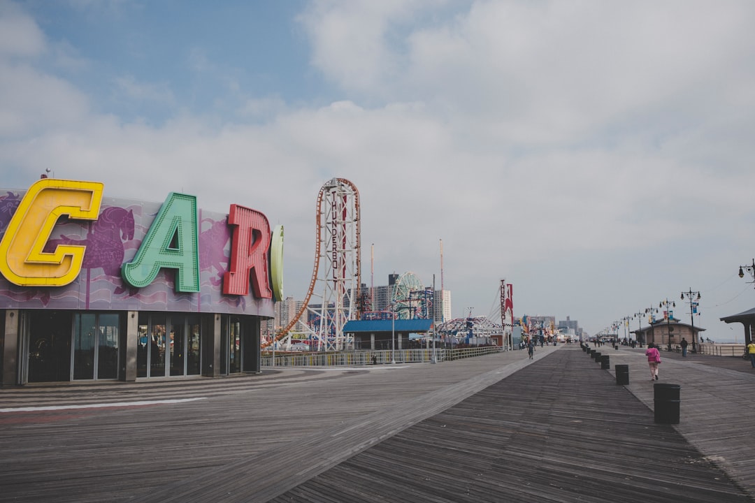 The Wonder Wheel and amusement park rides at Coney Island, Brooklyn, visible from the Riegelmann Boardwalk with Atlantic Ocean in background