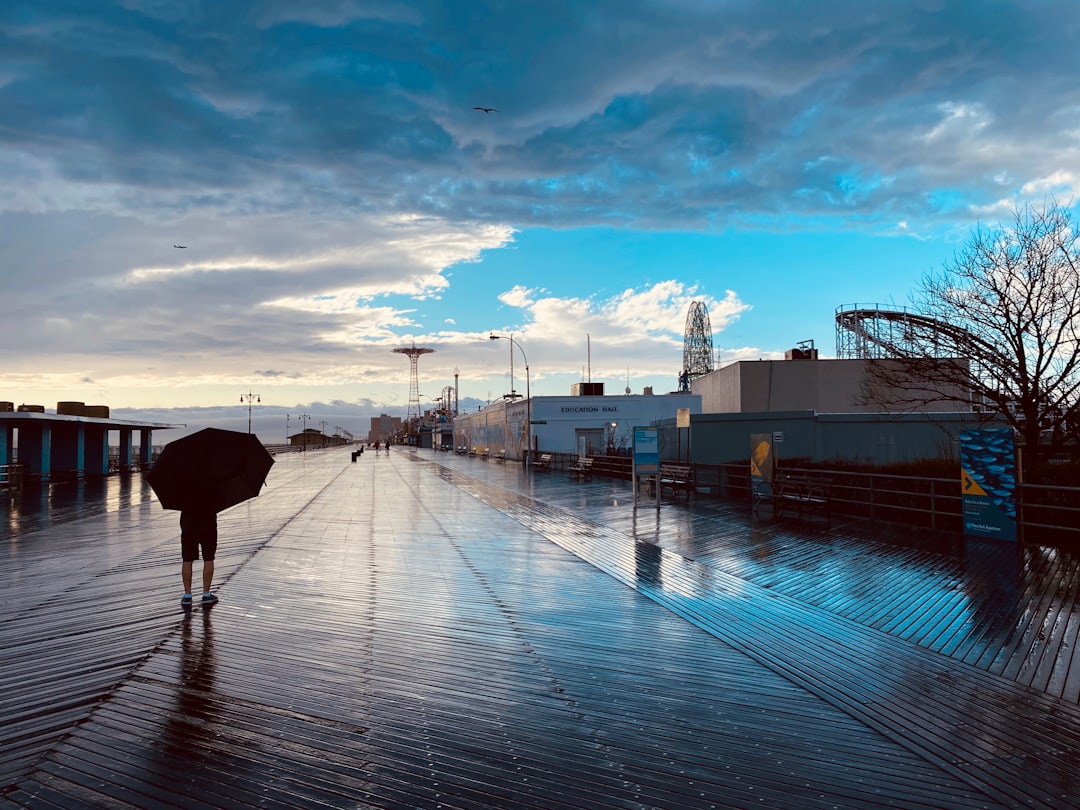 The Riegelmann Boardwalk looking east along the Atlantic Ocean, with the wide wooden promenade empty on a quiet morning in Coney Island, Brooklyn