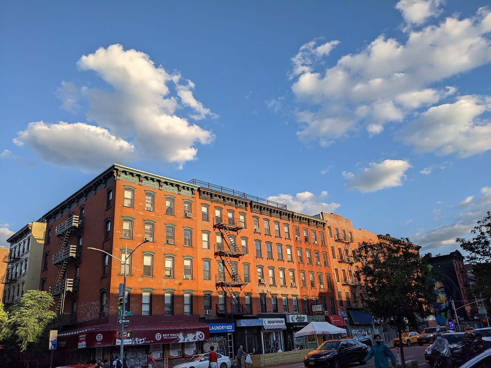 Five-story brick tenement buildings along First Avenue in the East Village, showing the characteristic fire escapes, cast-iron lintels, and continuous street wall that defines the neighborhood