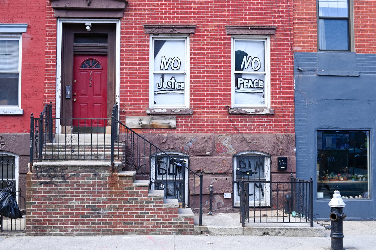 A stoop and entrance of a Brooklyn attached rowhouse with brick facade and iron railings, the kind of two-family home that defines Farragut's ownership culture