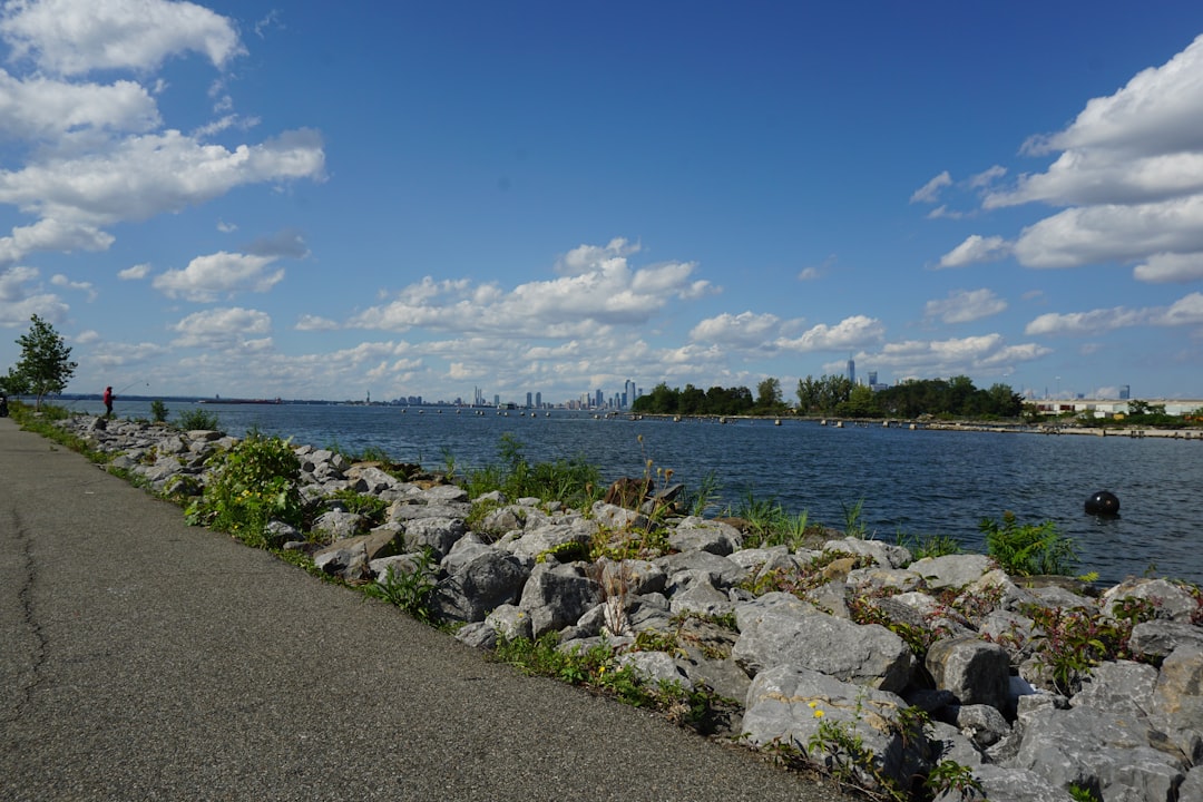 A person riding a bike on a path next to a waterway, representing the Marine Park trail system along Gerritsen Creek that borders the neighborhood
