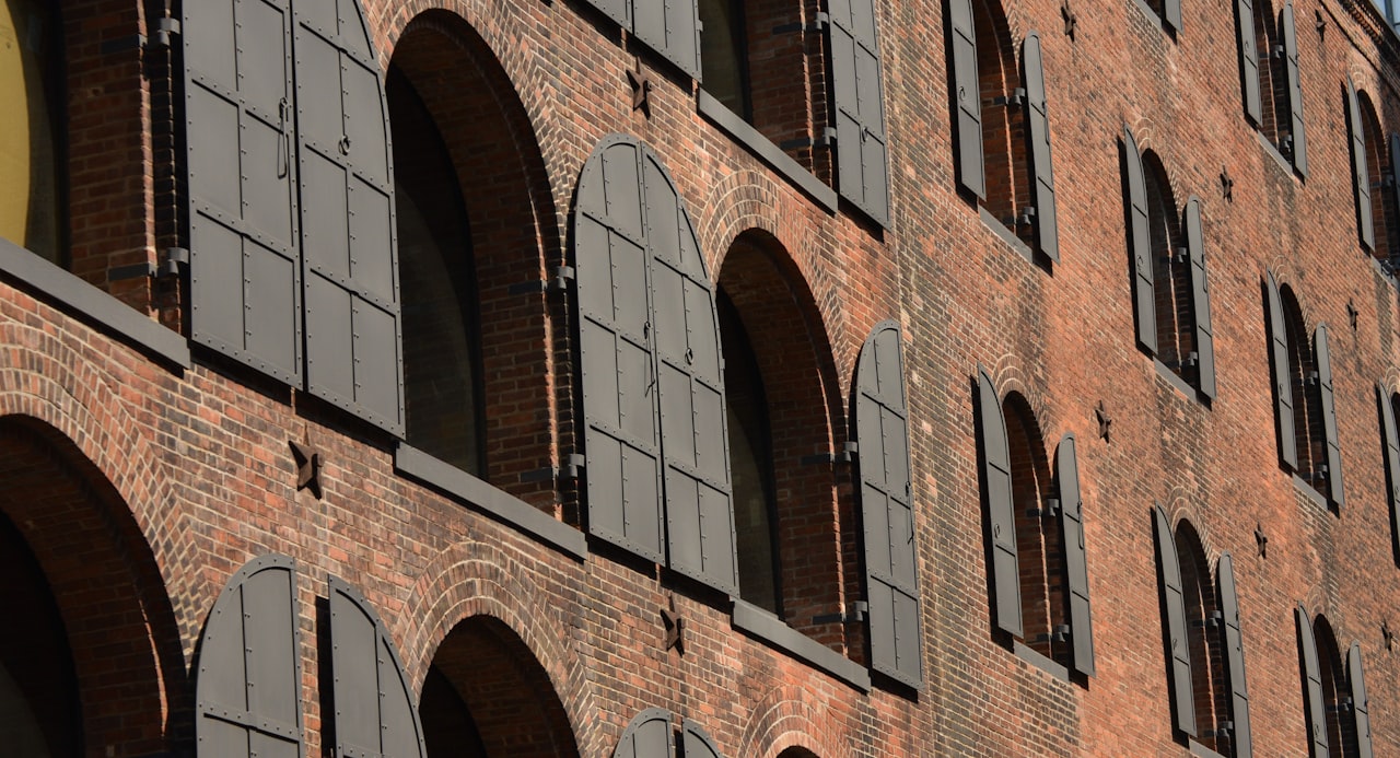A converted red brick warehouse building in Gowanus Brooklyn with large industrial windows and painted facade detail, representing the neighborhood's manufacturing heritage alongside new residential development