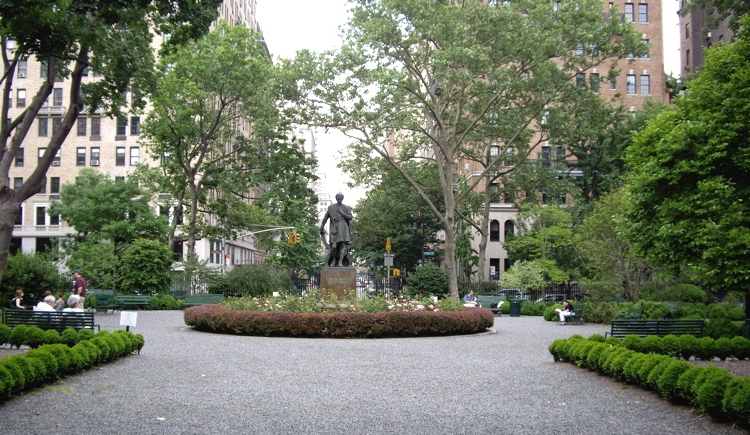The Victorian cast-iron fence and gate of Gramercy Park, the only private park in Manhattan, with mature trees and formal plantings visible through the bars