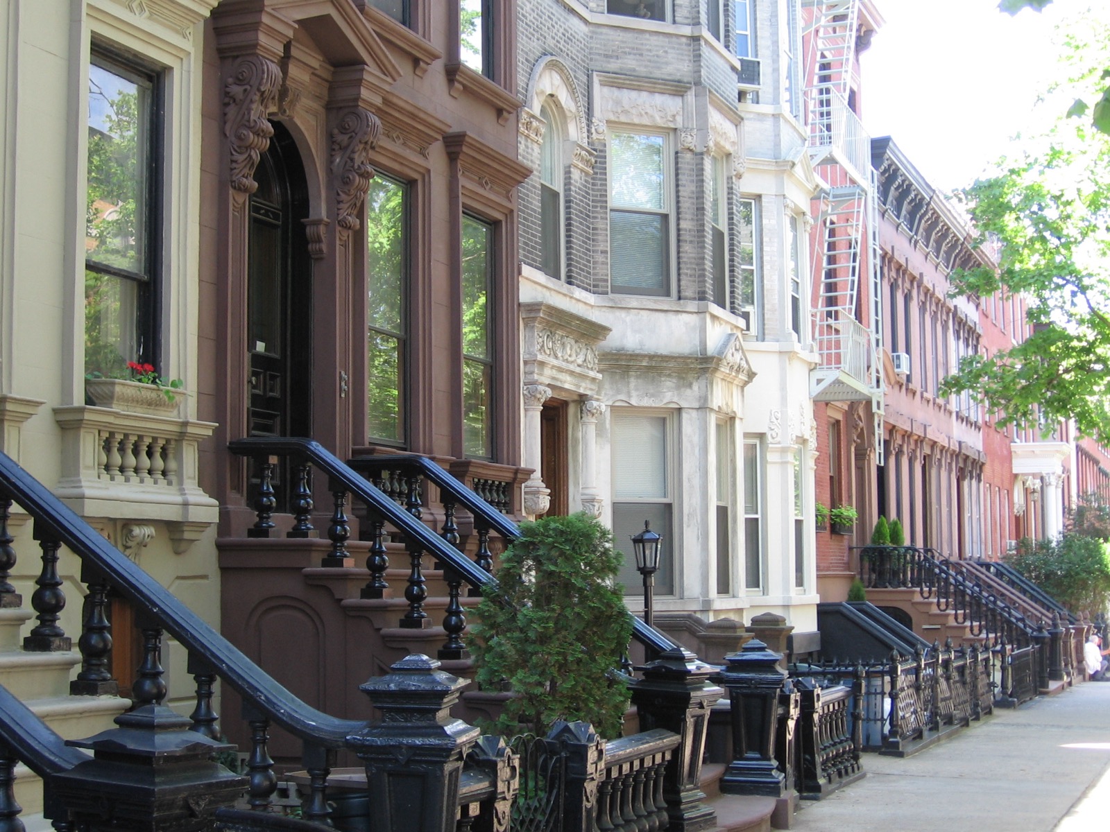 Wood-frame row houses in the Greenpoint Historic District with painted clapboard siding, Italianate bracketed cornices, and arched windows characteristic of 1850s and 1860s construction