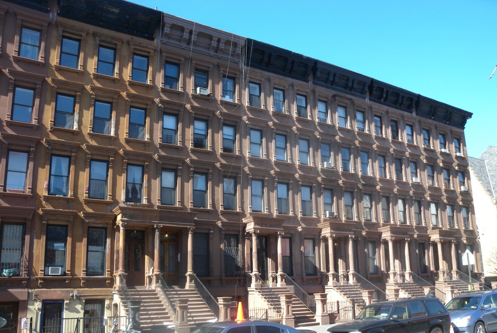 Brownstone rowhouses on Lenox Avenue in Harlem, the same blocks that housed the Savoy Ballroom era and still define the neighborhood's streetscape