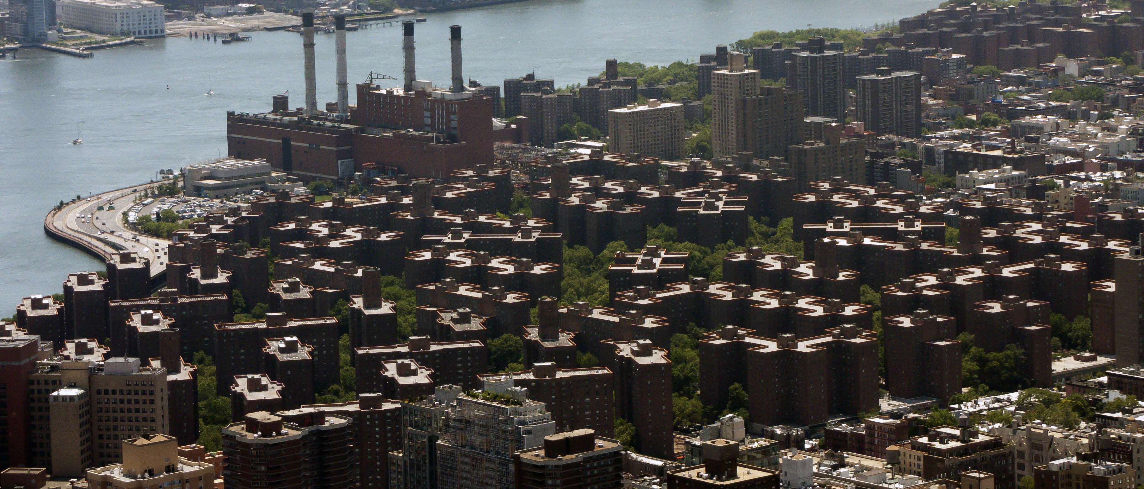 Aerial view of the Peter Cooper Village superblock showing the 21 red-brick towers surrounded by open green space with the East River and FDR Drive at the eastern edge