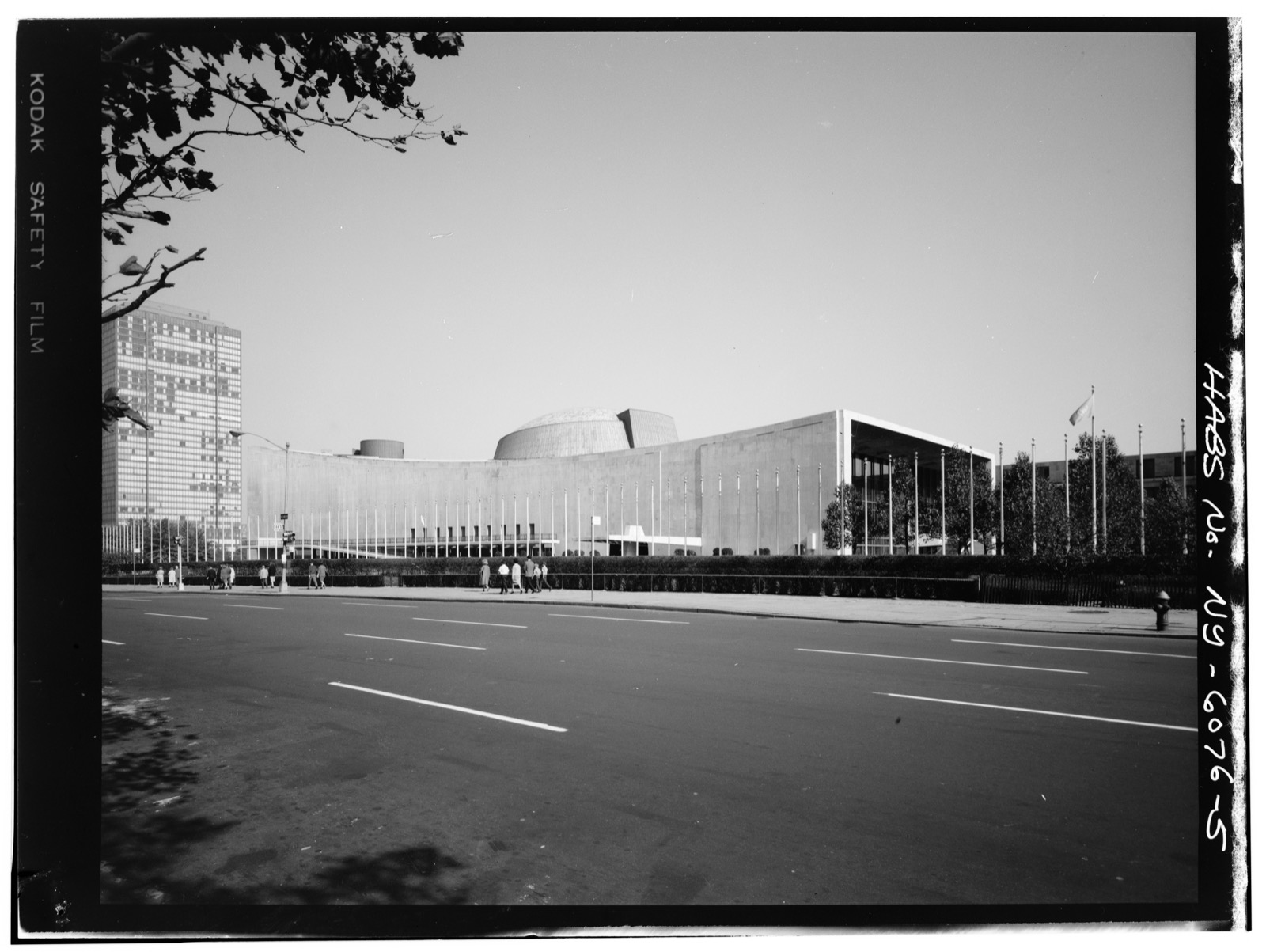A black and white archival photograph of the domed United Nations General Assembly Building with the Secretariat tower rising behind it