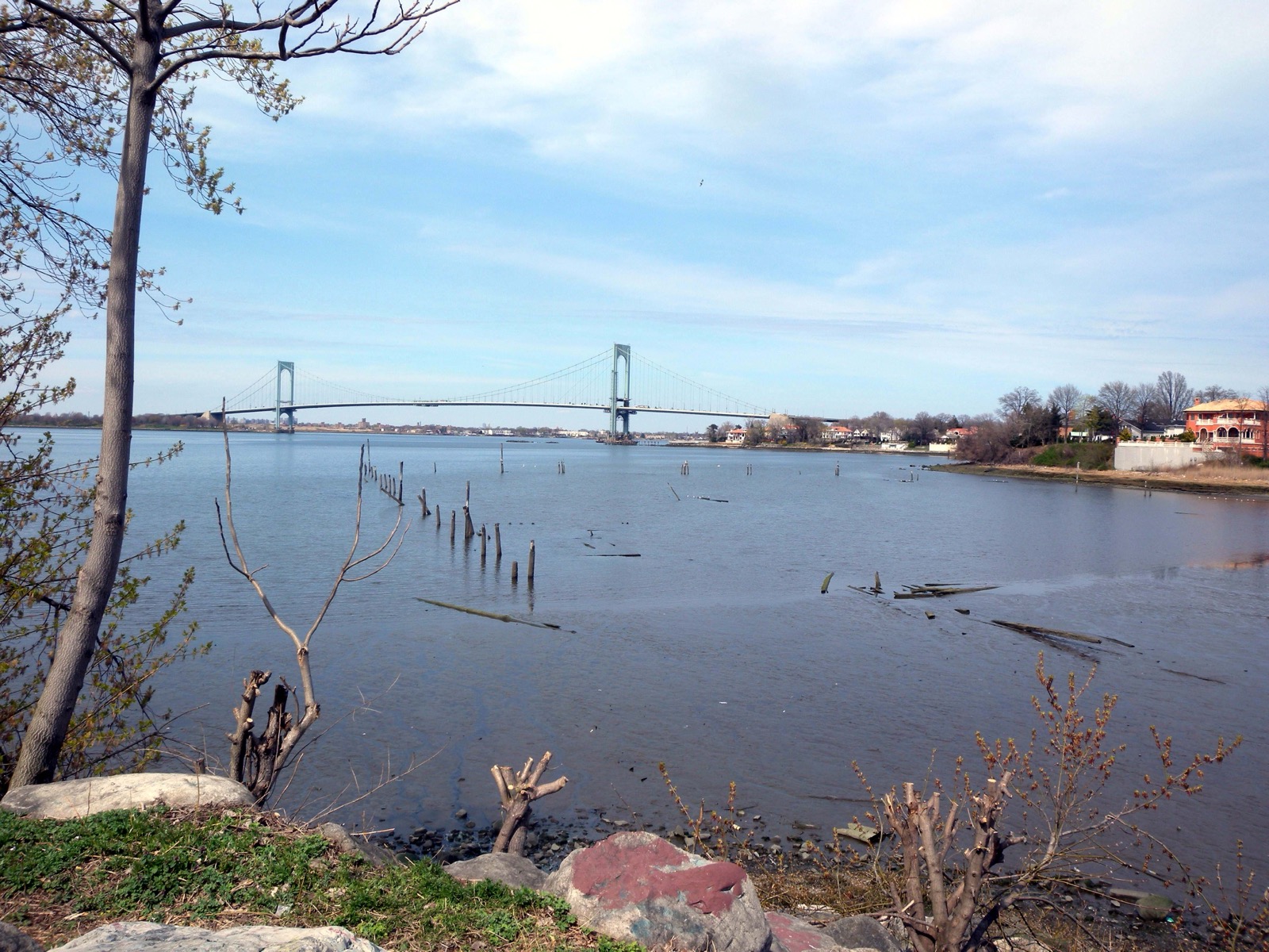 Rocky shoreline at Powells Cove in Whitestone looking across open water at the Bronx-Whitestone Bridge