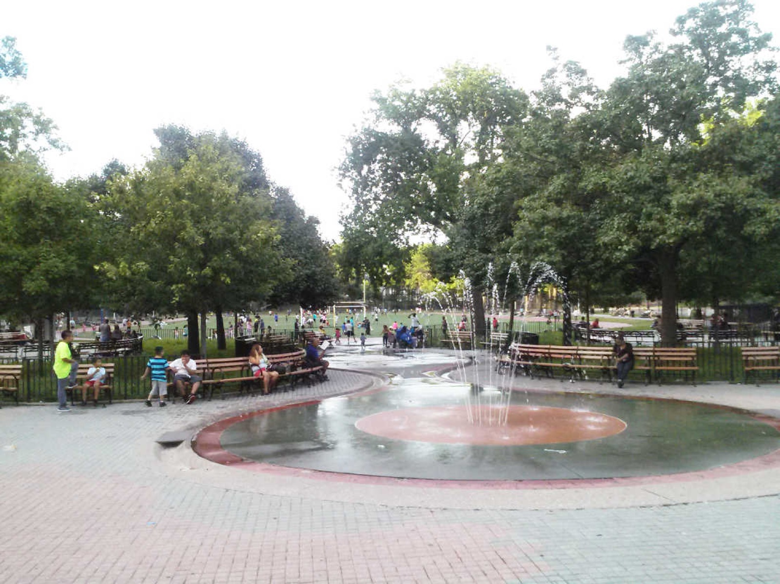 The Williamsbridge Oval park in summer showing the open green space and running track with surrounding residential buildings framing the former reservoir basin